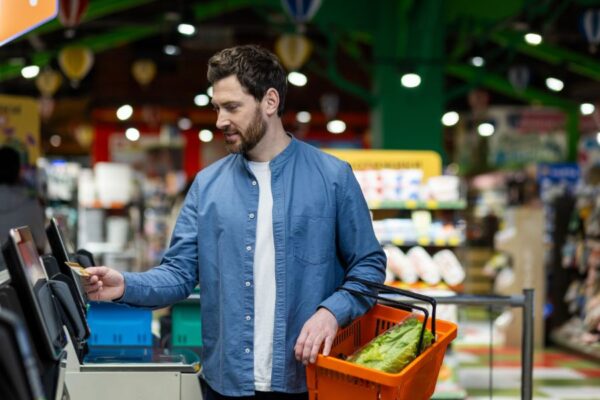 male customer using the self-checkout lane in the grocery store