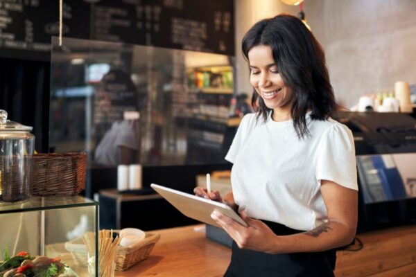 A restaurant manager smiling while using a tablet